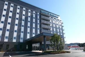 a hotel building with a sign on the front of it at Hotel Route-Inn Shinshiro in Shinshiro