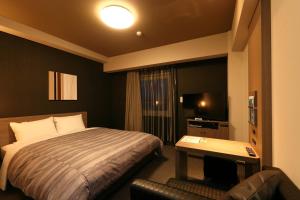 a hotel room with a bed and a television at Hotel Route-Inn Shinshiro in Shinshiro