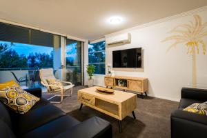 a living room with a couch and a table at Chancellor Lakeside Apartments in Gold Coast