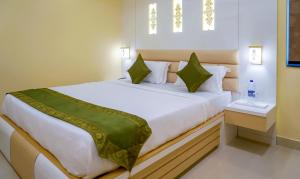 una camera da letto con un grande letto bianco con cuscini verdi di Treebo Trend Oasis Cuttack Puri a Bhubaneshwar