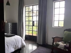 a bedroom with two windows and a bed and a chair at Little Fields Country House and Cottages in Howick