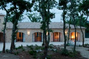 una casa de piedra con árboles delante de ella en LE MAS DES SOURIS BLONDES en Labastide-de-Virac