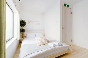 a white bedroom with a bed and a window at Momodani House 501 in Osaka