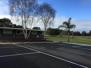 a parking lot with a tennis court in front of a building at Manjimup Gateway Hotel in Manjimup