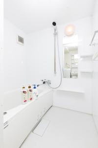 een witte badkamer met een douche en een wastafel bij Momodani House 501 in Osaka
