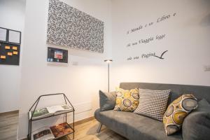 uma sala de estar com um sofá cinzento e uma placa na parede em Dolce Vita Affittacamere em Roma
