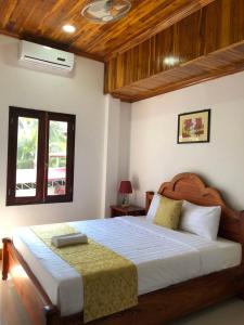 a bedroom with a large bed with a wooden ceiling at Elephant Boutique Hotel in Luang Prabang