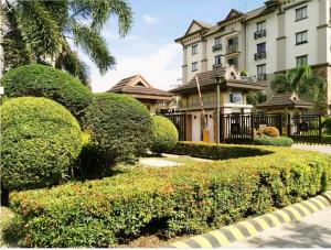 a building with a hedge in front of a house at Ecowest Condo beside SM Mall in Davao City