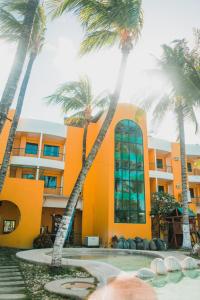 a yellow building with palm trees in front of it at Country Village Hotel in Cagayan de Oro