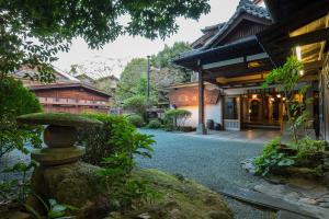 a garden with a stone fountain in front of a building at Hitoyoshi Ryokan in Hitoyoshi