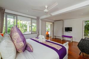 1 dormitorio con 1 cama grande con almohadas moradas en Villa Eindra, en Seminyak