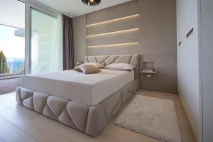 a bedroom with a large white bed with a large window at Opatija Deluxe Apartment with swimming pool in Opatija