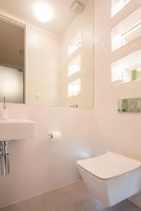 a white bathroom with a toilet and a sink at Opatija Deluxe Apartment with swimming pool in Opatija