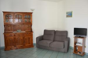 sala de estar con silla y TV en Appartamento Li Puntiti 1 en Budoni