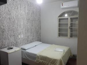 a small bedroom with a bed and a window at Araca Hotel in Araçatuba