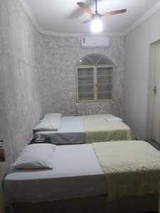 a bedroom with three beds and a ceiling fan at Araca Hotel in Araçatuba