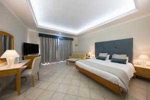 a bedroom with a large bed and a desk and a computer at Paradise Bay Resort in Mellieħa