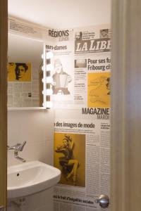 a bathroom with a sink and newspapers on the wall at Hotel Alpha in Fribourg