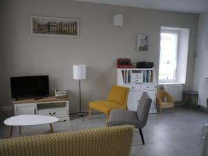 PruniersにあるGite au Coeur de la Sologneのリビングルーム(テレビ、椅子、テーブル付)