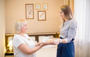 a woman holding a plate of food next to another woman at Гостиница Бастон на Герцена in Tomsk