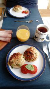 two biscuits on a plate with tomatoes and a cup of juice at Penmaenmawr Bed & Breakfast in Penmaen-mawr