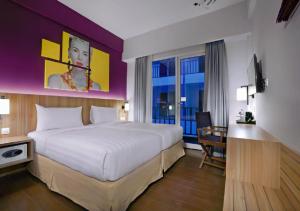 a hotel room with a large bed and a window at Fame Hotel Sunset Road in Kuta