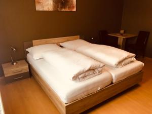 uma cama com lençóis brancos e almofadas em Gästehaus Auer Fritzi em Jois