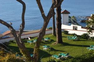 un complexe avec des chaises et l'océan en arrière-plan dans l'établissement Quinta Da Penha De Franca, à Funchal