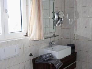 La salle de bains est pourvue d'un lavabo blanc et d'un miroir. dans l'établissement Grimm's Lodge, à Lörrach