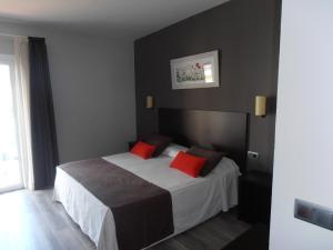 a bedroom with a bed with two red pillows at Hotel Marblau Tossa in Tossa de Mar