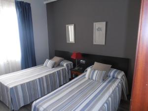 a bedroom with two beds and a lamp on a table at Hotel Marblau Tossa in Tossa de Mar