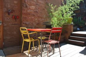 uma mesa com três cadeiras e uma mesa e cadeiras vermelhas em Natangora em Marcillac-Vallon