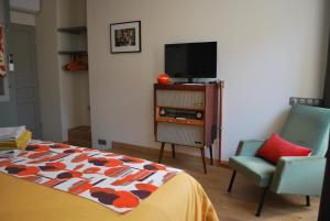 um quarto com uma cama, uma televisão e uma cadeira em Natangora em Marcillac-Vallon