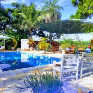 una piscina con due sedie bianche e un ombrellone di Pousada da Lua São Pedro a São Pedro