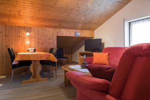 a living room with a red couch and a table at Apartments Orphelja in Saas-Grund