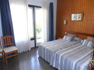 a bedroom with a bed and a chair and a window at Hotel Marblau Tossa in Tossa de Mar