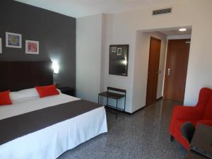 a hotel room with a bed and a red chair at Hotel Marblau Tossa in Tossa de Mar