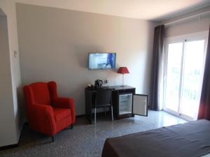 a hotel room with a red chair and a television at Hotel Marblau Tossa in Tossa de Mar