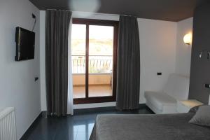 a bedroom with a bed and a window with a balcony at Hotel El Salt in Valderrobres