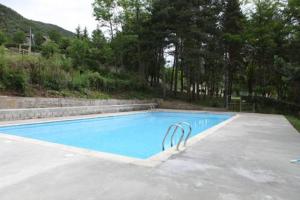 a large swimming pool with blue water and trees at Casa de Colònies Vall de Boí - Verge Blanca in Llesp