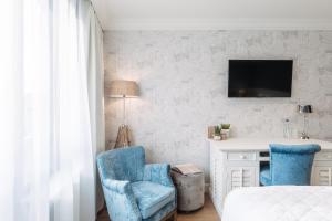 a bedroom with blue chairs and a desk and a tv at Hotel Cocoon in Ostend