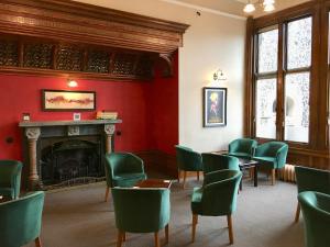 a waiting room with green chairs and a fireplace at Louisa Lodge & Purbeck House Hotel in Swanage