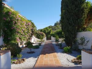 a garden with pink flowers and a brick walkway at Casa Fuente de la Zorra in Alora
