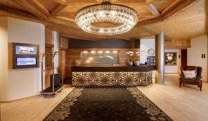 a living room with a chandelier and a bar at Hotel Piz Buin Klosters in Klosters