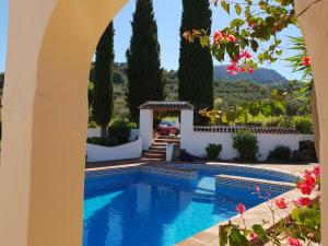 a pool in a villa with trees and flowers at Casa Fuente de la Zorra in Alora