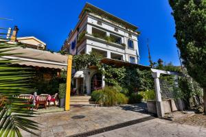a white building with a table and chairs in front of it at Villa Velzon Guesthouse in Budva