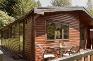 cabina con mesa y sillas en la cubierta en Caol Gleann Lodge, en Rowardennan