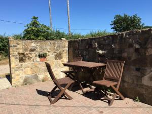 a wooden table and two chairs next to a stone wall at New Stable Cottage in Cowes