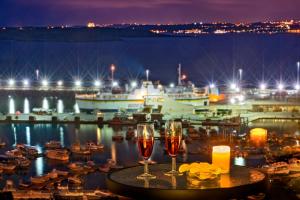 two glasses of wine on a table next to a harbor at Grand Hotel Gozo in Għajnsielem