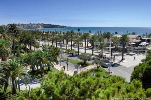 uma vista para um parque com palmeiras e o oceano em Alexis Basic em Salou